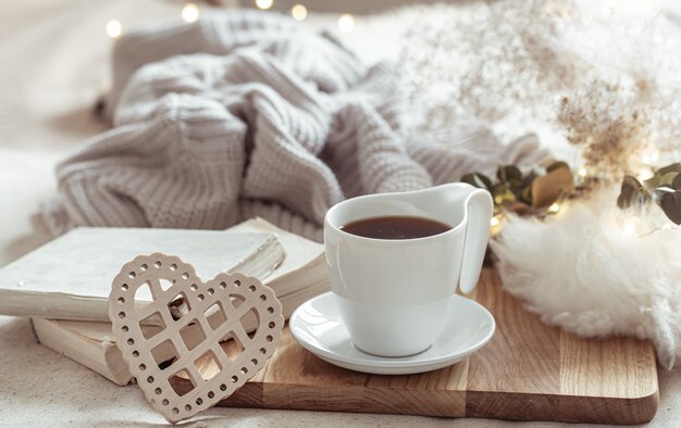 Composición acogedora con una taza de café en un platillo y detalles de decoración del hogar.