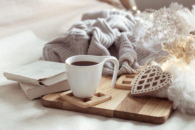 Composición acogedora con una taza de café en un platillo y detalles de decoración del hogar.