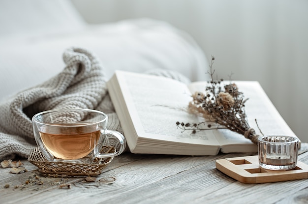 Composición acogedora con una taza de té y un libro en el interior de la habitación.