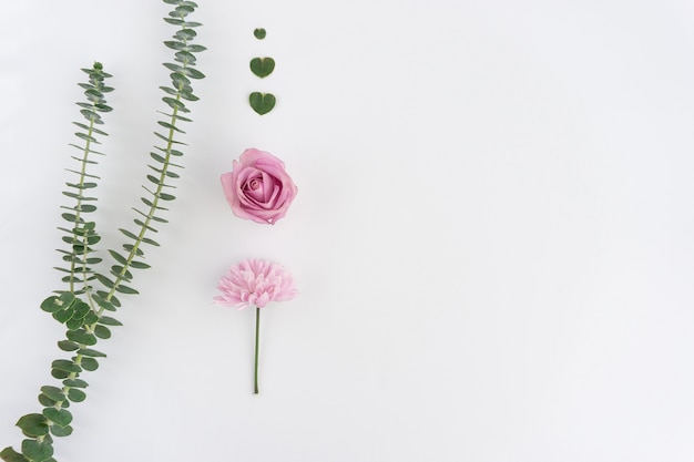 Composición bonita con dos flores y corazones florales verdes