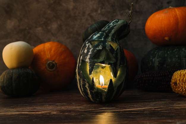 Foto gratuita composición con calabaza verde tallada y vela encendida