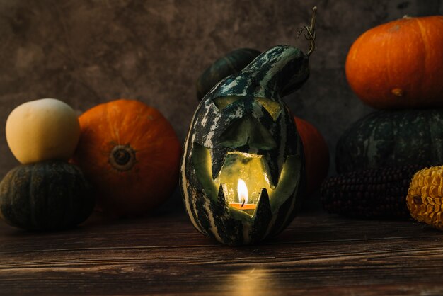 Composición con calabaza verde tallada y vela encendida