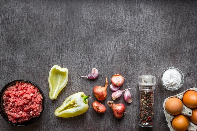 Composición de carne cruda con verduras y especias sobre fondo de madera