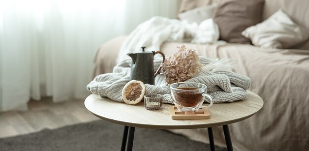 Composición de la casa de otoño con una taza de té, una tetera y un elemento de punto.