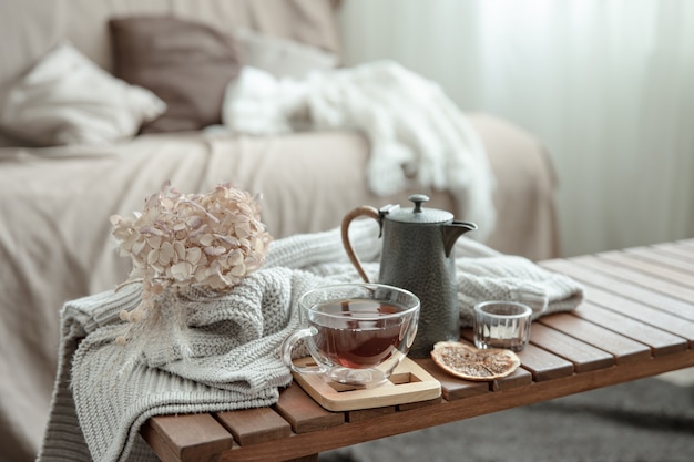 Composición de la casa de otoño con una taza de té, una tetera y un elemento de punto.