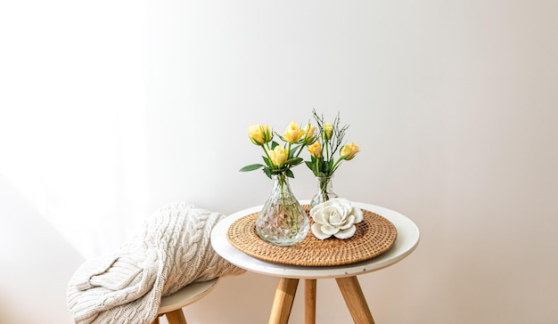 Composición casera con flores en un jarrón en el interior de una habitación blanca.