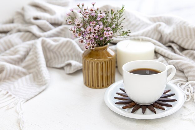 Composición casera con una taza de café, una vela y un ramo de flores.