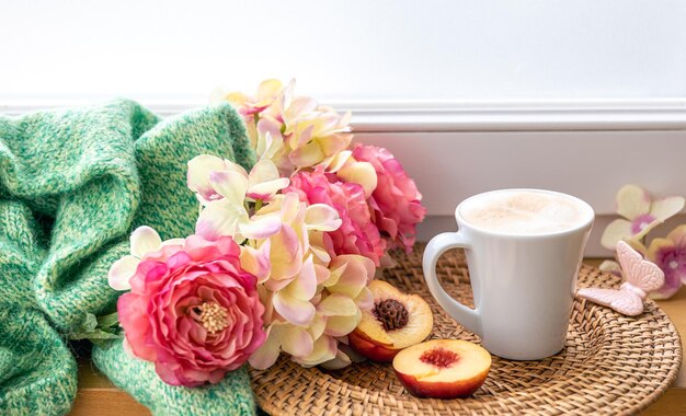 Composición casera con una taza de flores de café y un elemento de punto.