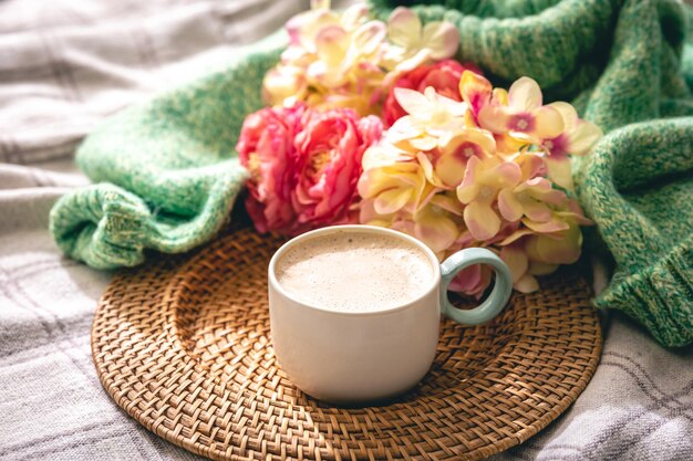 Composición casera con una taza de flores de café y un elemento de punto.