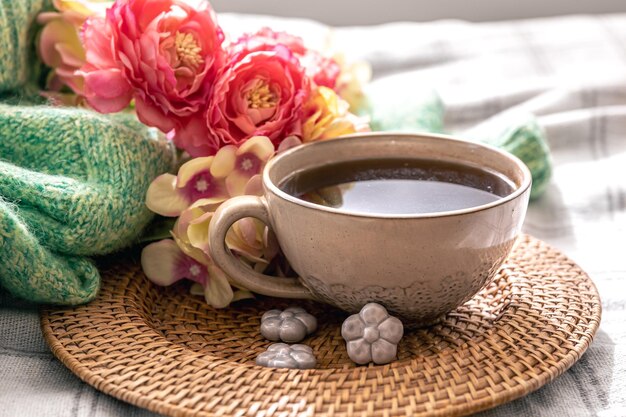 Composición casera con una taza de flores de té y un elemento de punto en la cama.