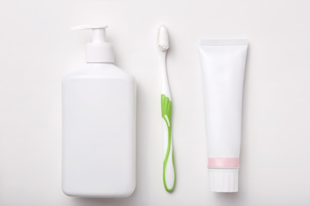 Composición del cepillo de dientes, pasta de dientes y una botella de jabón o gel aislado en blanco. Productos cosméticos. Lay Flat