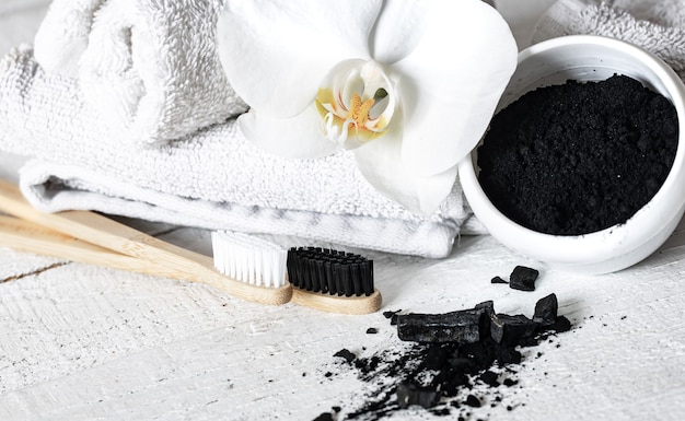 Composición con cepillos de dientes naturales de madera, polvo blanqueador de dientes negros y espacio de copia de flores de orquídeas.