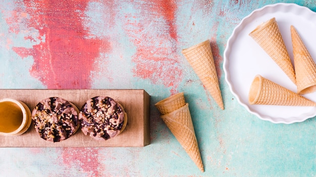 Composición de conos de obleas en blanco y helado en tazas sobre fondo de colores