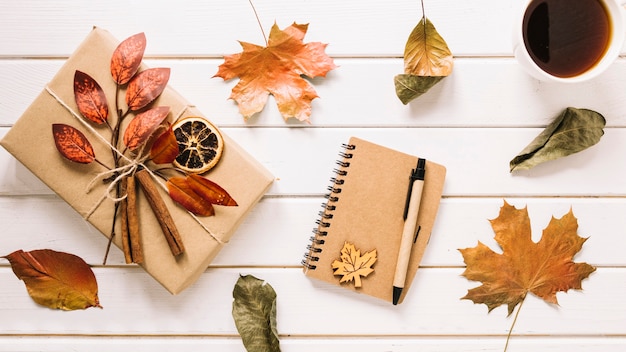 Composición creativa de otoño con regalo, cuaderno y té