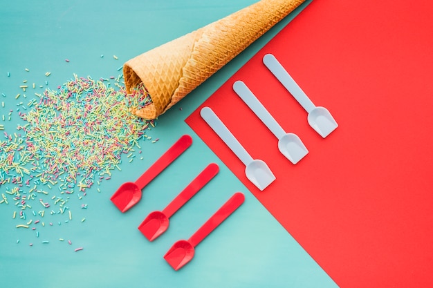 Composición de cumpleaños con cono de helado, confeti y cucharas