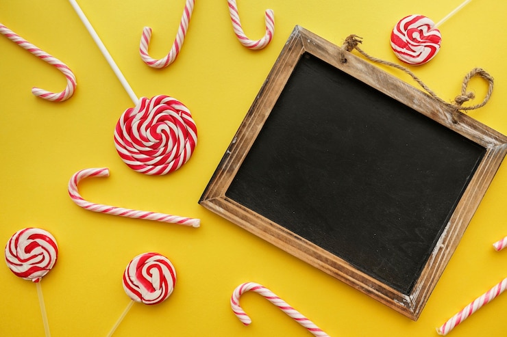 Foto gratuito composición de cumpleaños con pizarra, bastones de caramelo y piruletas