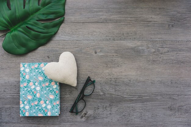 Composición decorativa con hoja de palma, libro y gafas