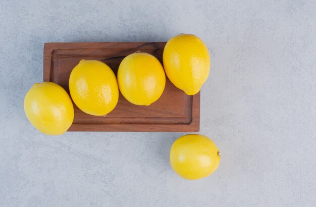 Composición de deliciosos limones sobre tabla de madera.