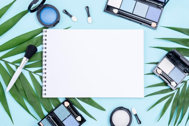 Composición de diferentes productos de belleza vista superior con libreta vacía