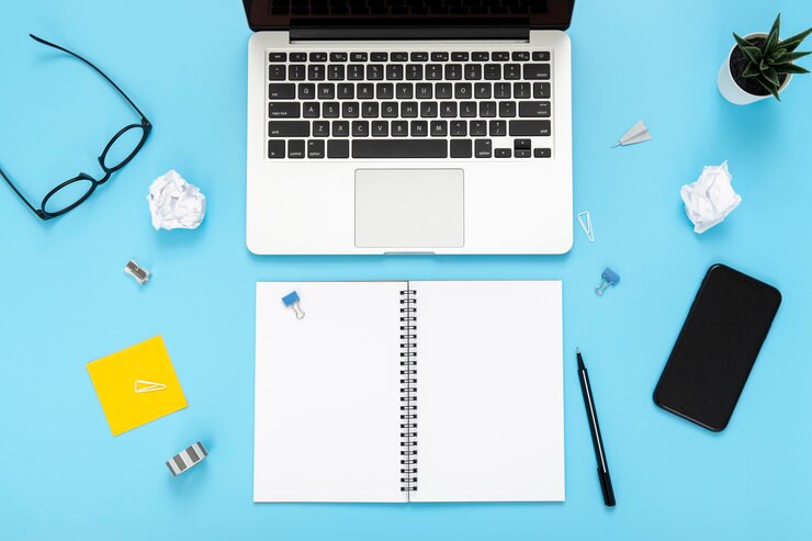 Foto gratuito composición de elementos de escritorio sobre fondo azul con cuaderno vacío