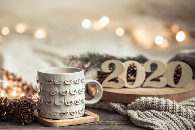 Composición festiva con taza blanca y guirnalda ligera.