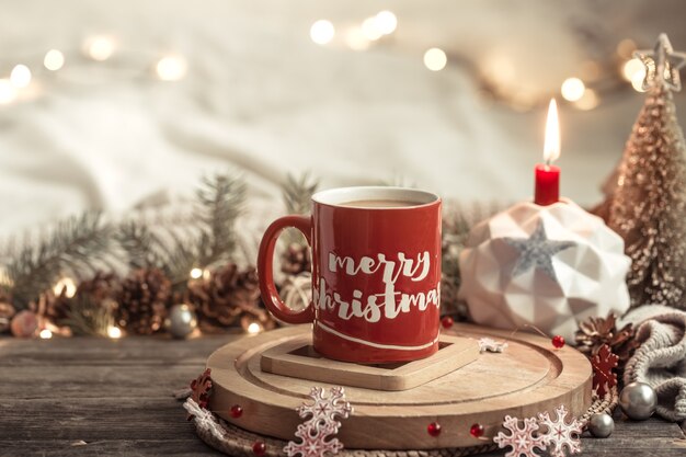 Composición festiva con una taza roja con inscripción de Feliz Navidad.
