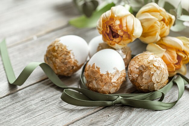 Composición festiva para las vacaciones de Pascua con huevos decorados y flores frescas.