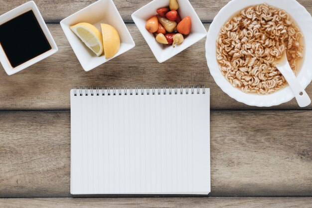 Composición flat lay de comida asiática con libreta