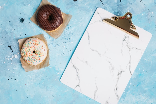 Foto gratuita composición flat lay de donuts con portapapeles