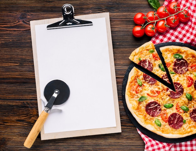 Composición flat lay de pizza con plantilla de portapapeles
