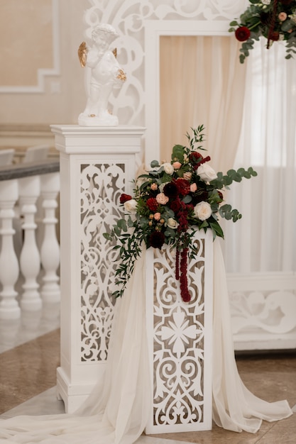 Foto gratuita composición floral en el arco blanco en el salón ceremonial de la boda