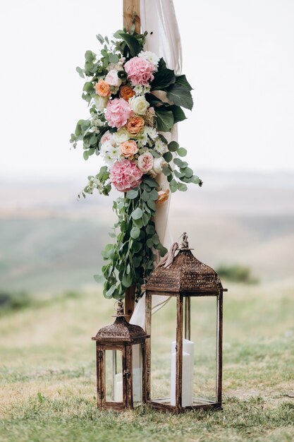 Composición floral hecha de eucalipto y tiernas flores rosadas con velas al aire libre