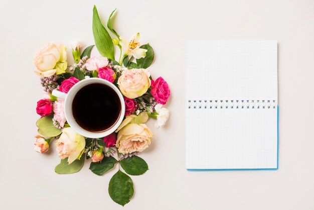 Composición de flores y bebidas cerca del cuaderno