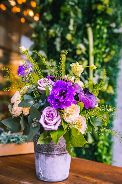 Composición de flores en el cubo de crema y rosas moradas vista lateral lithianthus