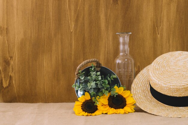 Composición de flores con cubo y sombrero