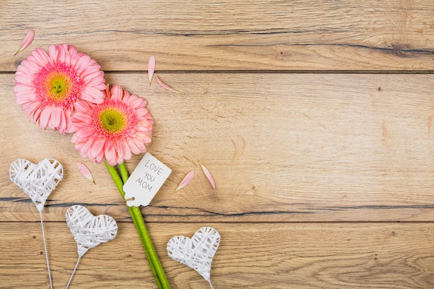 Composición de flores frescas con etiqueta cerca de corazones ornamentales en varitas