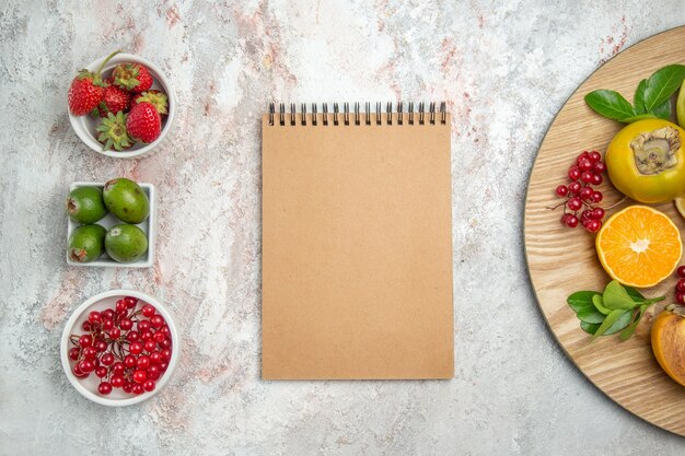 Composición de la fruta de la vista superior con el bloc de notas en el color del árbol maduro de la fruta de la mesa blanca fresca