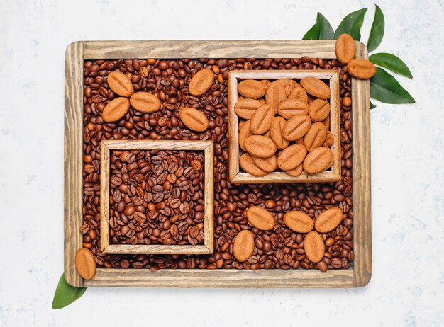 Composición con granos de café tostados y galletas con forma de grano de café sobre una superficie clara.