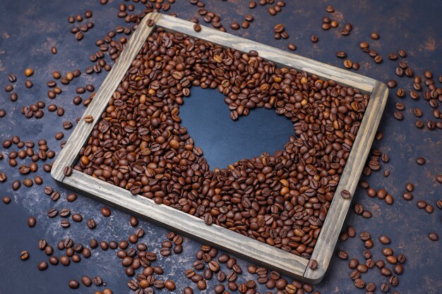 Composición con granos de café tostados y galletas con forma de grano de café sobre una superficie de color marrón oscuro