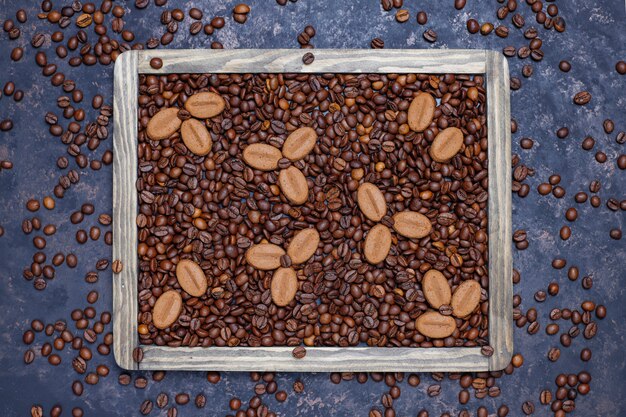 Composición con granos de café tostados y galletas con forma de grano de café sobre una superficie de color marrón oscuro