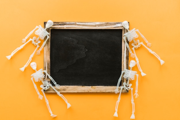 Foto gratuita composición de halloween con pizarra y esqueletos