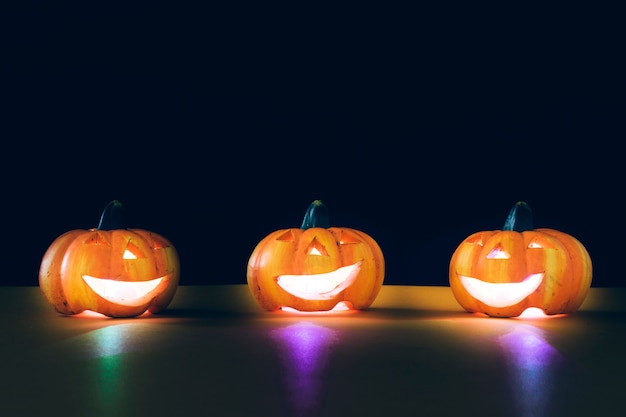 Composición para halloween con tres calabazas iluminadas