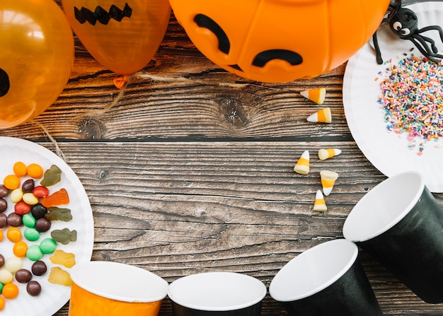 Foto gratuita composición de halloween con vasos de papel y dulces