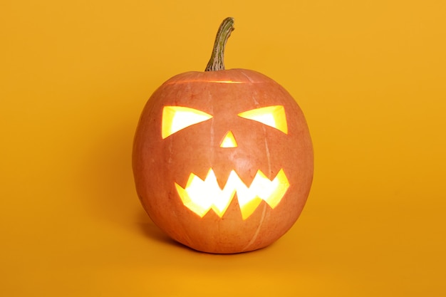 Composición de la luz brillante desde el interior de Jack o Lantern, calabaza isoalted en amarillo, celebrando las vacaciones, la noche de octubre pasado, naranja calabaza en la pared del estudio. Concepto de halloween