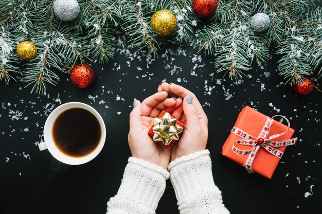 Composición de navidad con café y manos sujetando regalo