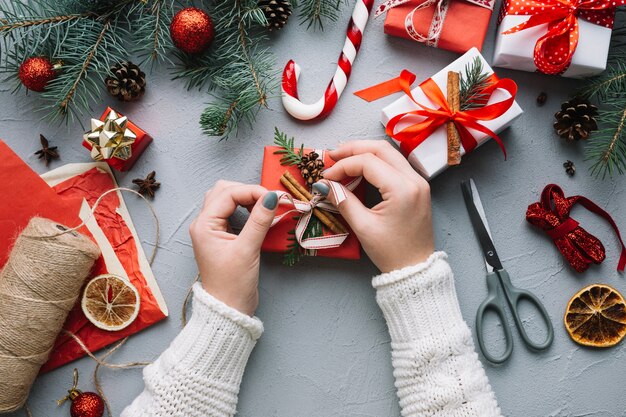 Composición de navidad con manos decorando regalo