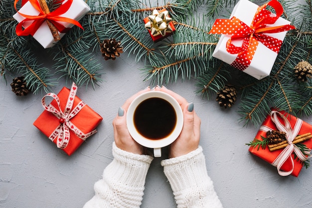 Composición de navidad con manos sujetando café y regalos