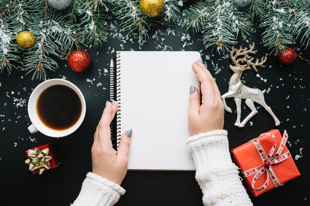 Composición de navidad con manos tocando libreta