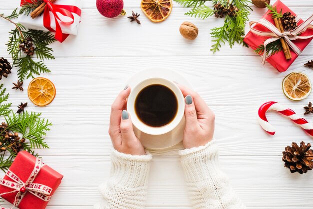 Composición de navidad con manos tocando taza de café