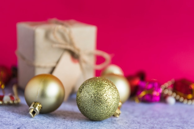 Composición navideña de adornos de oro con caja de regalo pequeña.